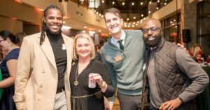 Alumni stand together at the Boar's Head Holiday Event