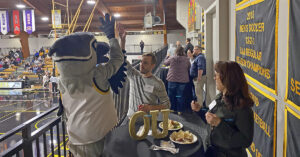 Petey the Petrel gives a high five to cheering alumni