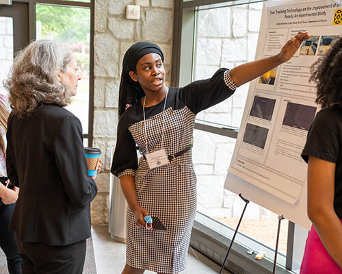 A student demonstrates her research to Dr. McClymond.